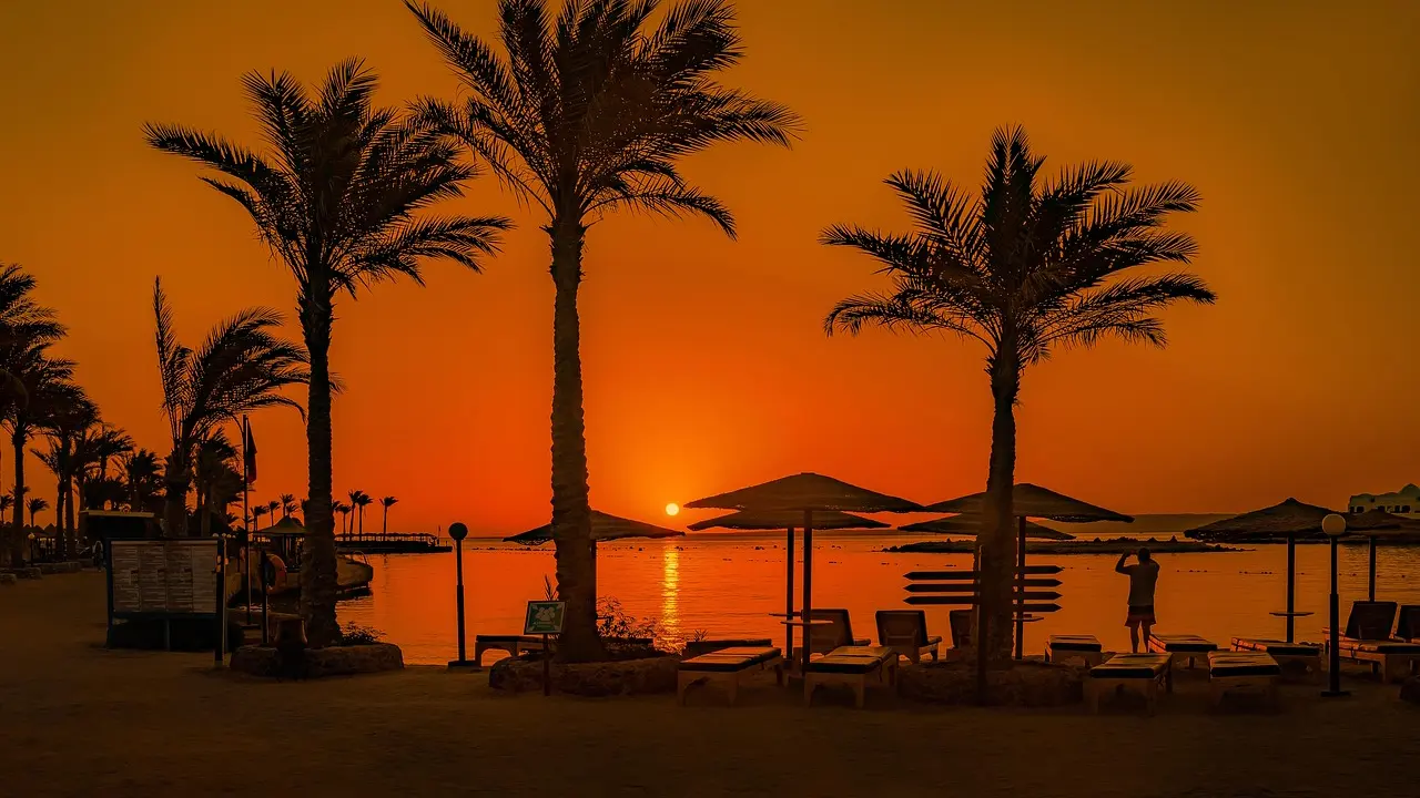 Beach loungers and umbrellas on white sand beside turquoise water