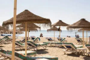 Beach loungers and umbrellas on white sand beside turquoise water