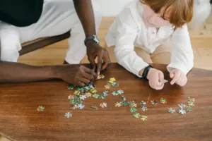 Person solving a jigsaw puzzle on a wooden table